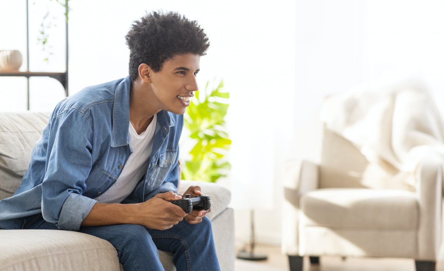 Happy african american guy playing video games at home